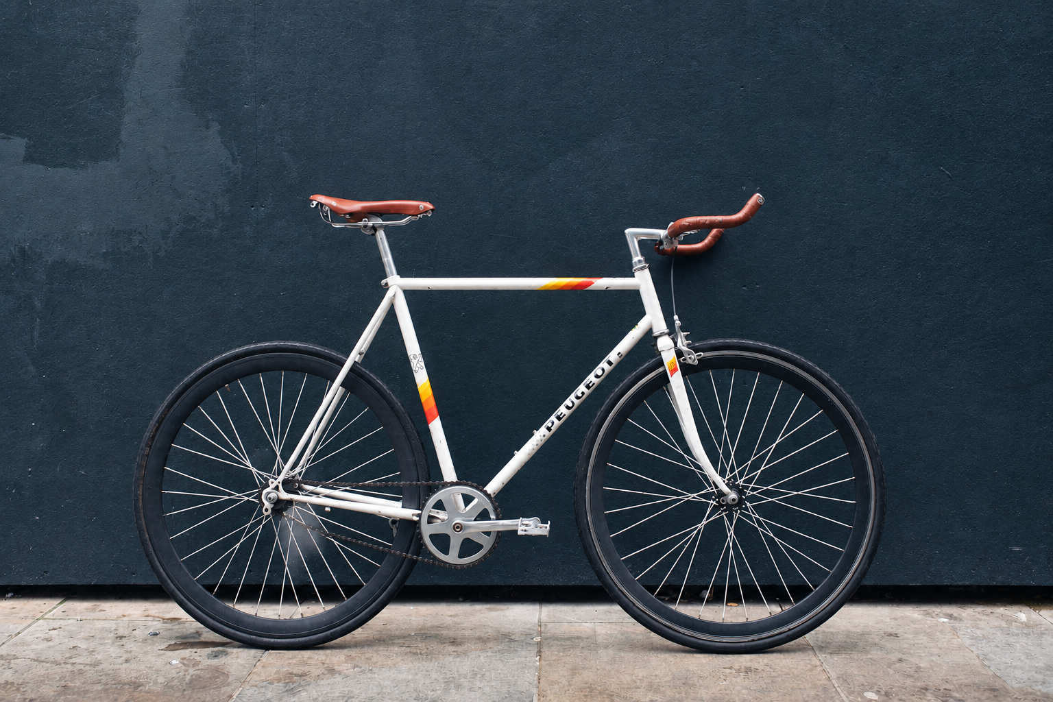 White bicycle against a dark wall, after light, color and clarity
